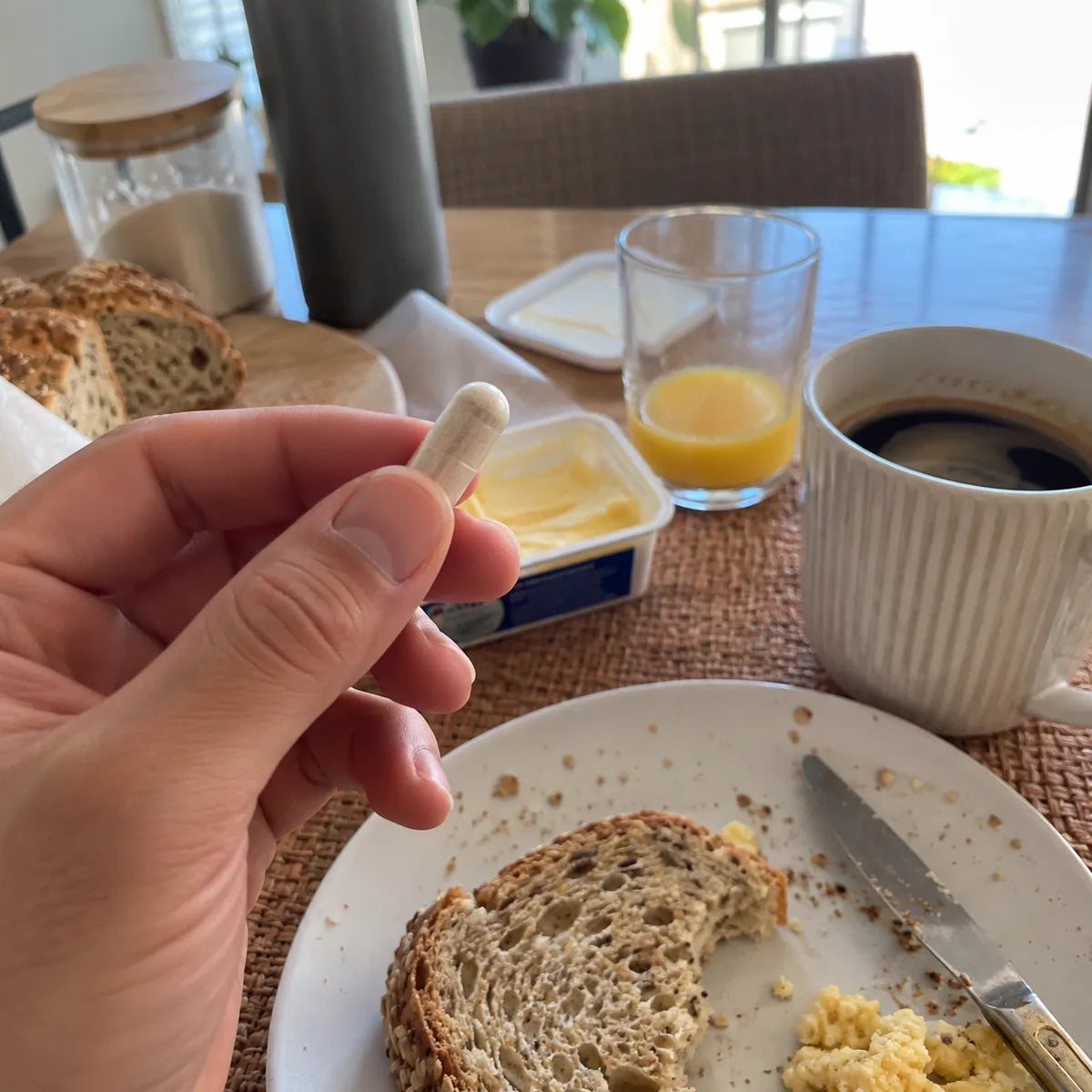 Una cápsula en la mano, junto al desayuno